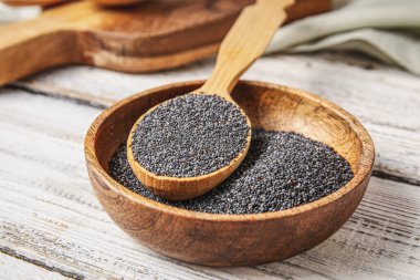 Hafif ahşap arka planda haşhaş tohumlu kase ve kaşık