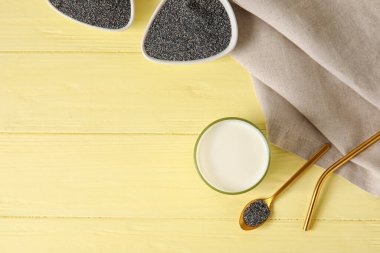 Haşhaş tohumlu kaşık ve tahta arka planda bir bardak süt.