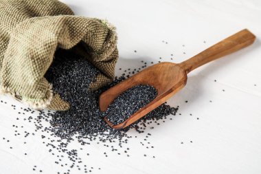 Hafif ahşap zemin üzerinde haşhaş tohumları olan poşetler ve kepçeler