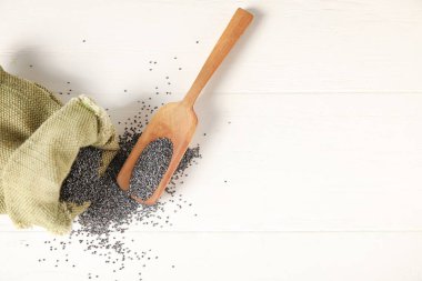 Hafif ahşap zemin üzerinde haşhaş tohumları olan poşetler ve kepçeler