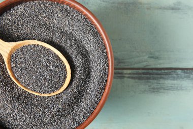 Ahşap arka planda haşhaş tohumlu kase ve kaşık