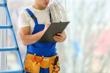 Genç elektrikçi odada panoya yazı yazıyor.