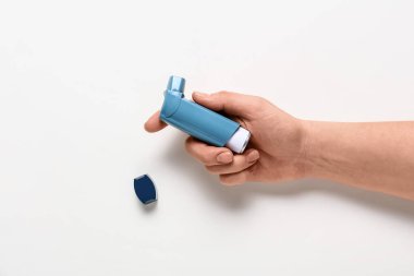 Beyaz arkaplanda astım spreyi olan kadın eli