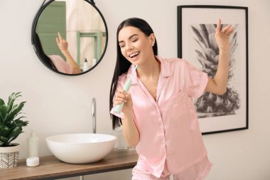 Banyoda dişlerini fırçalayan genç bir kadın.