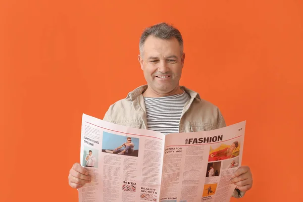 Mature man with newspaper on color background