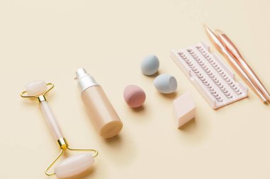Renk arkaplanında masaj aracı olan makyaj malzemeleri kümesi