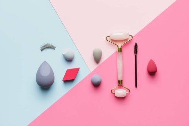 Renk arkaplanında masaj aracı olan makyaj malzemeleri kümesi