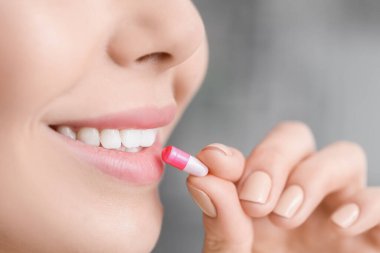 Evde hap alan güzel bir genç kadın, yakın plan.