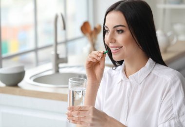 Genç ve güzel bir kadın mutfakta hap alıyor.