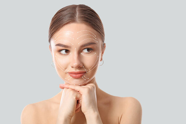 Молодая женщина со стрелками для массажа на лице на светлом фоне