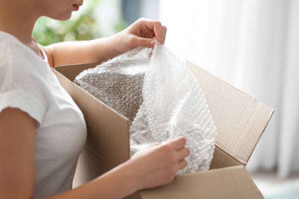 Молодая женщина распаковывает посылку дома, крупным планом