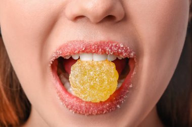 Şeker dudaklı güzel genç bir kadın jöle yiyor, yakın plan.
