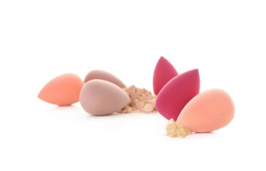 Farklı makyaj süngerleri ve temel örnekleri ve beyaz arka planda pudra