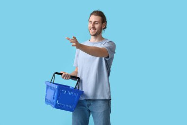 Arka planda boş alışveriş sepeti olan genç bir adam.