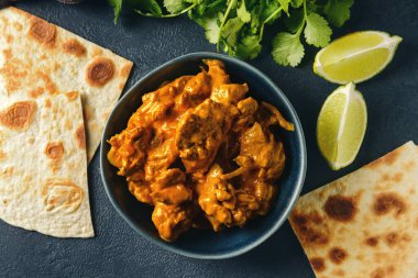 Koyu arkaplanda bir kase lezzetli tavuk tikka masala.