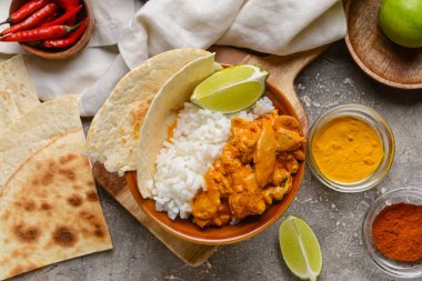 Bir kase lezzetli tavuk tikka masala ve arkaplanda pilav.