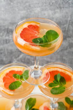 Gri arka planda greyfurt kokteyli olan gözlüklerden yapılmış kule, yakın plan.