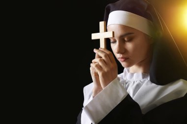 Karanlık arka planda dua eden genç rahibe.