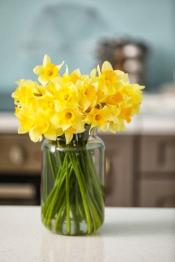 Mutfaktaki masasında güzel nergisler olan vazo.