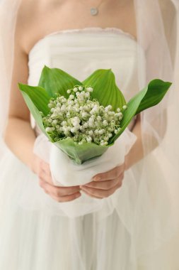 Gelin, açık arkaplanda güzel çiçekleri olan bir buket çiçekle