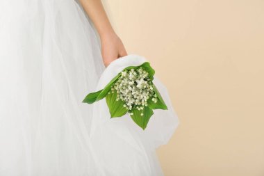 Gelin, açık arkaplanda güzel çiçekleri olan bir buket çiçekle