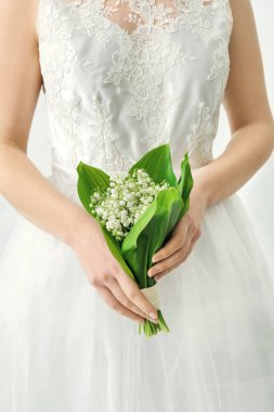 Gelin, açık arkaplanda güzel çiçekleri olan bir buket çiçekle