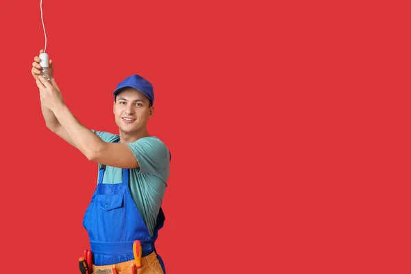 Young Electrician Screwing Light Bulb Color Background — Stock Photo, Image