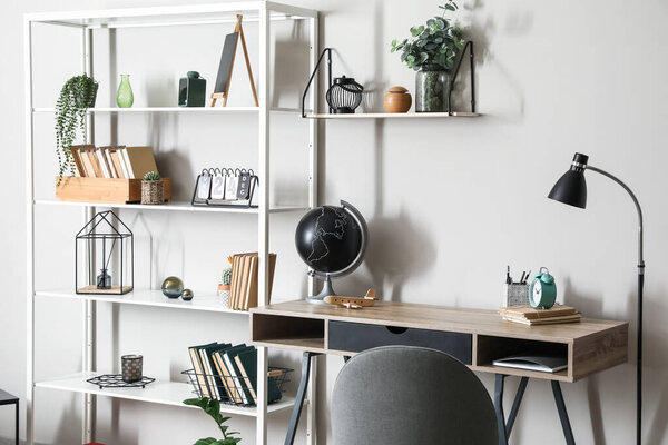 Modern workplace and book shelf near light wall