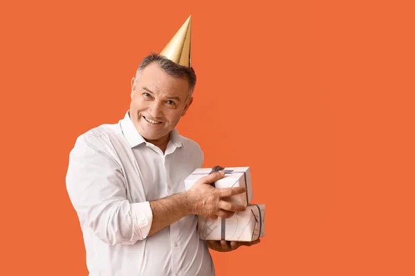 Glücklich Reifer Mann Partyhut Und Mit Geschenken Auf Farbigem Hintergrund — Stockfoto