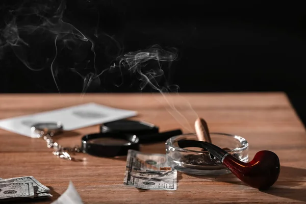 Ash tray, pipe and money on table of detective