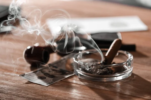 Ash tray, pipe and money on table of detective