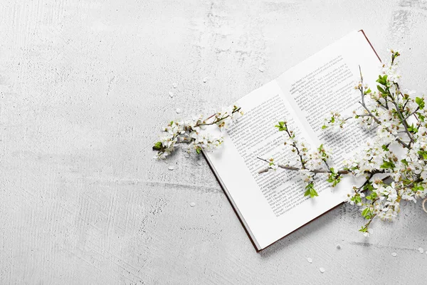 Beautiful blooming branches and book on light background