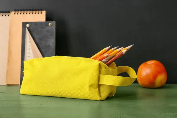 Pencil case and stationery on dark background