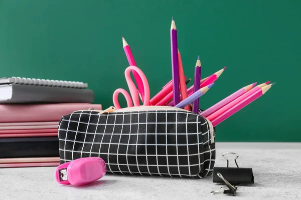 Pencil case and stationery on color background