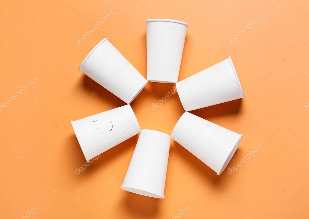 Frame made of blank paper cups on color background