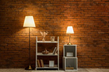 Parlak lambalar ve kitap rafı tuğla duvarın yanında.