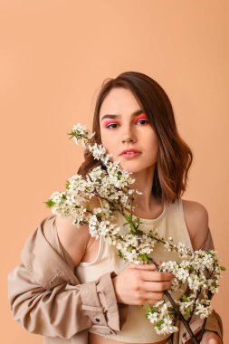 Renkli arka planda çiçek açan bahar dalları olan güzel genç bir kadın.