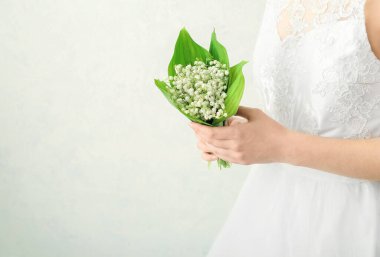 Gelin, açık arkaplanda güzel çiçekleri olan bir buket çiçekle