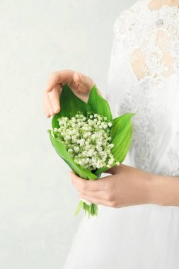 Gelin, açık arkaplanda güzel çiçekleri olan bir buket çiçekle