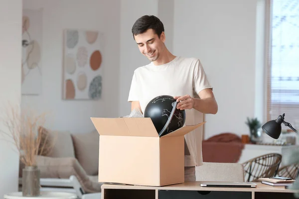Handsome Young Man Unpacking Box Globe Home — Stock Photo, Image