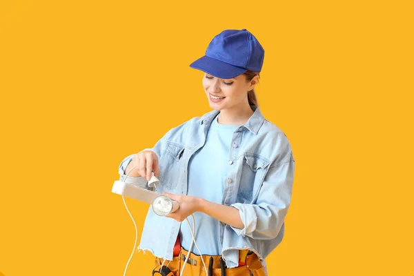 Young Female Electrician Plugging Light Bulb Outlet Color Background — Stock Photo, Image