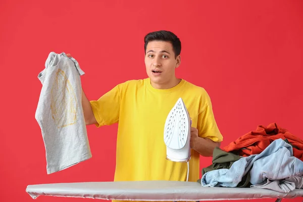 Shocked Young Man Ironing Clothes Color Background — Stock Photo, Image