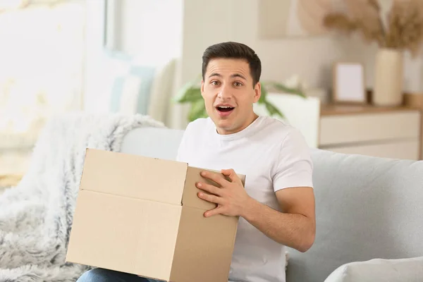 Surprised Young Man Unpacking Parcel Home — Stock Photo, Image