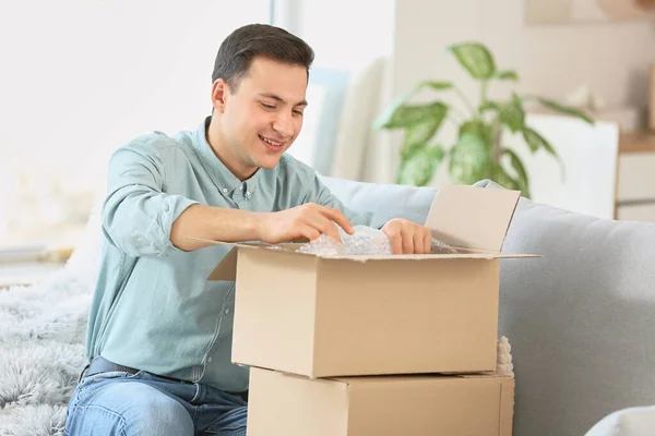 Happy Young Man Unpacking Parcel Home — Stock Photo, Image