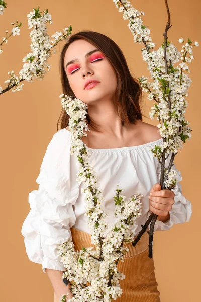 色の背景に春の枝を咲かせる美しい若い女性 — ストック写真