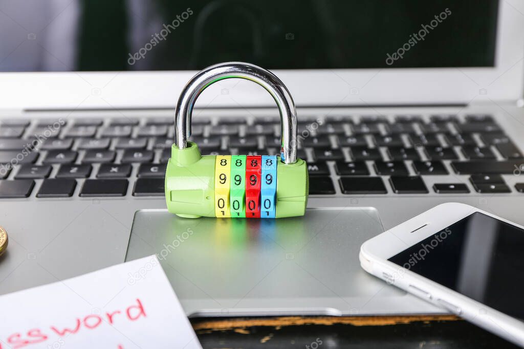 Laptop, phone and lock on table, closeup. Hacking concept