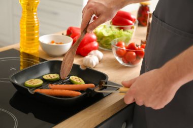 Mutfakta sosis ve kabak kızartan adam, yakın plan.