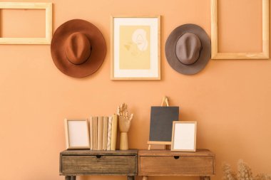 Renkli duvarda masalar ve şapkalar asılı şık bir oda.