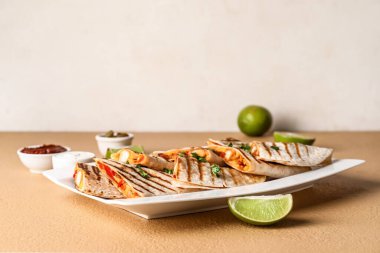 Lezzetli quesadillas, limon, sos ve turşulu jalapeno tabağı.