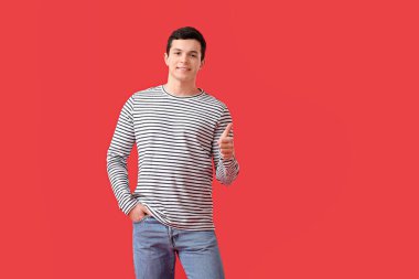 Yakışıklı genç adam renk arkaplanında başparmağını kaldırıyor